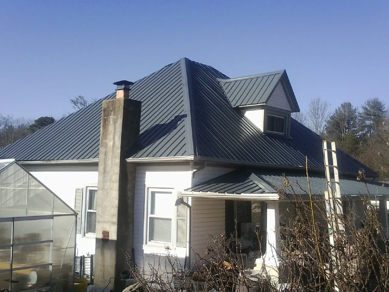 Dark blue standing seam metal roof on a white farmhouse with dormer — Slate & Tile Roof Repair by Roofing Brothers in Annawan