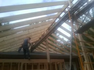 Rafters going up over a new addition with a worker on the wall in Annawan