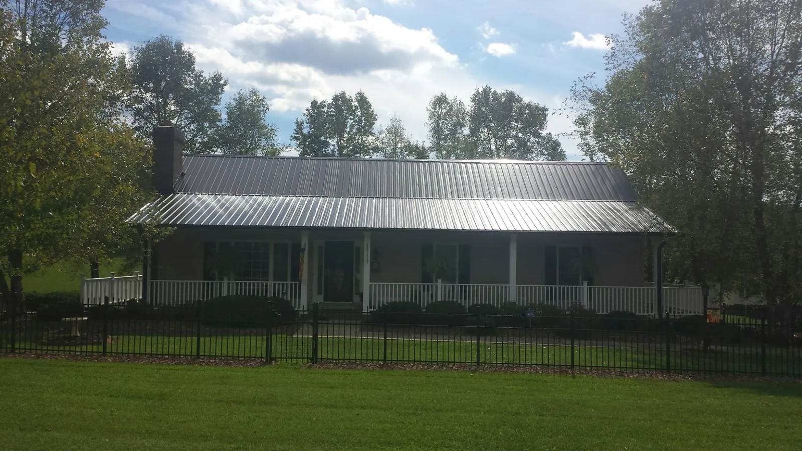 Gray metal roof on a brick ranch with a full width front porch — Gutter Guard Installation work by our crew in Annawan