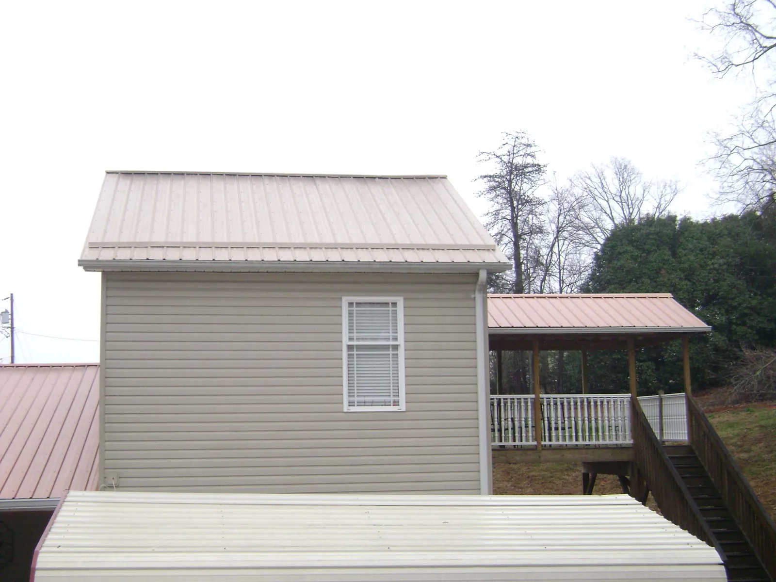 Tan metal roofs on a two story addition and attached porch, from a Roof Replacement job in Annawan