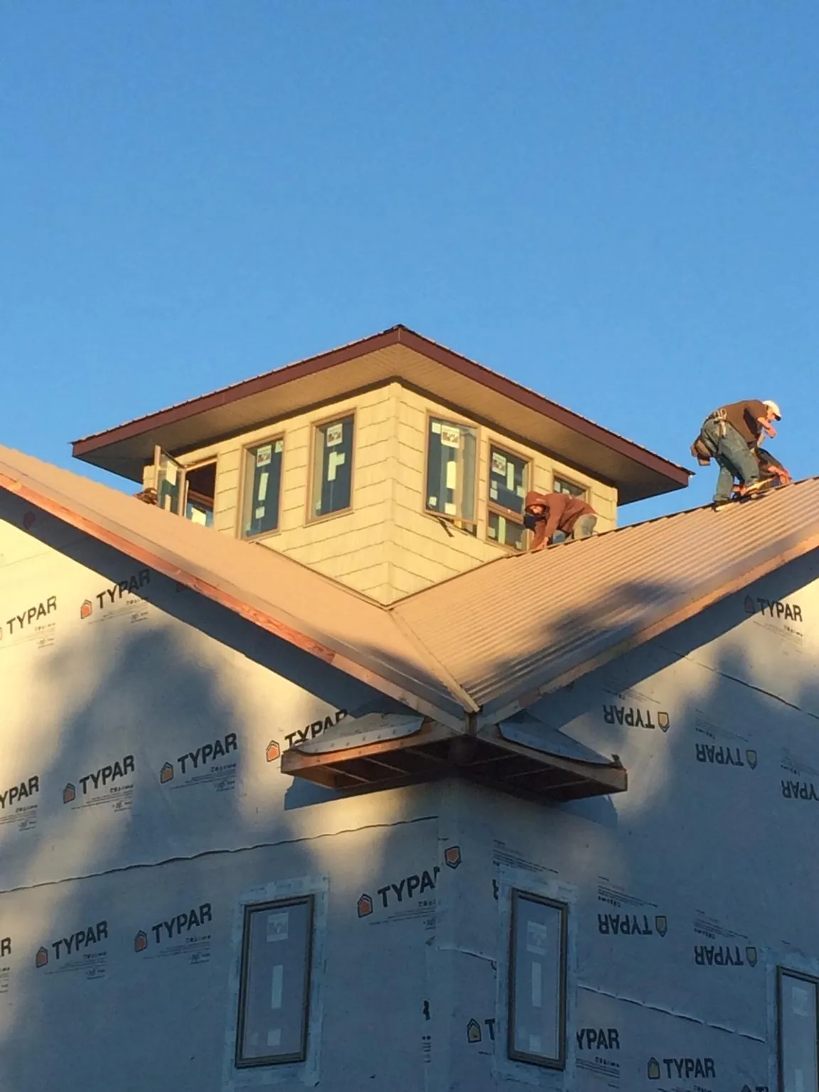 Roofers working around a rooftop cupola on a new metal roof at sunset — Roof Waterproofing in Annawan by Roofing Brothers